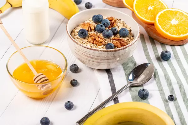 Healthy breakfast background on wooden table with oatmeal, fruit and honey