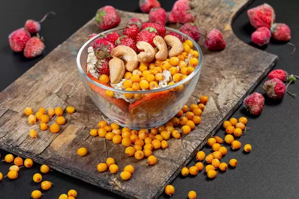 Healthy breakfast background with oatmeal, berries and cashews on an old wooden kitchen board (Flip 2020)