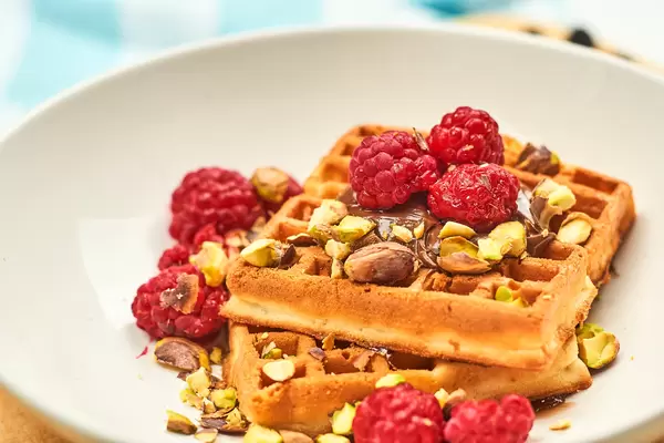 Healthy breakfast with sweet waffles covered with pista and raspberries