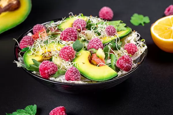 Healthy diet. Salad with raspberries and vegetables on a dark background (Flip 2020)