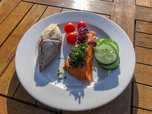 Healthy dinner with a piece of smoked salmon, salad topping, cucumber, tomatoes and a wholemeal bread roll