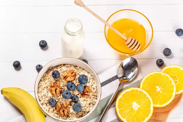 Healthy food concept, oatmeal with fruits, honey and milk for breakfast