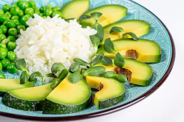 Healthy food concept- rice with vegetables and sunflower microgreen on a blue plate