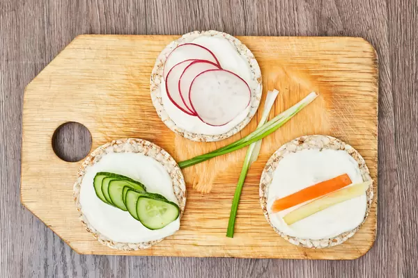 Healthy food - cucumber, radish and carrot slices with sour cream on crispbread