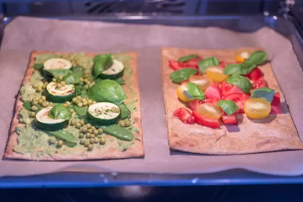 Healthy Food - two vegan pizzas with healthy toppings in the oven