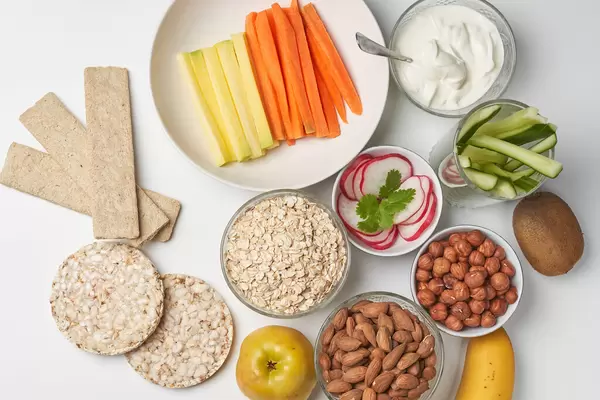 Healthy snack concept. Oatmeal bread, carrot sticks, nuts and fruits on the table.