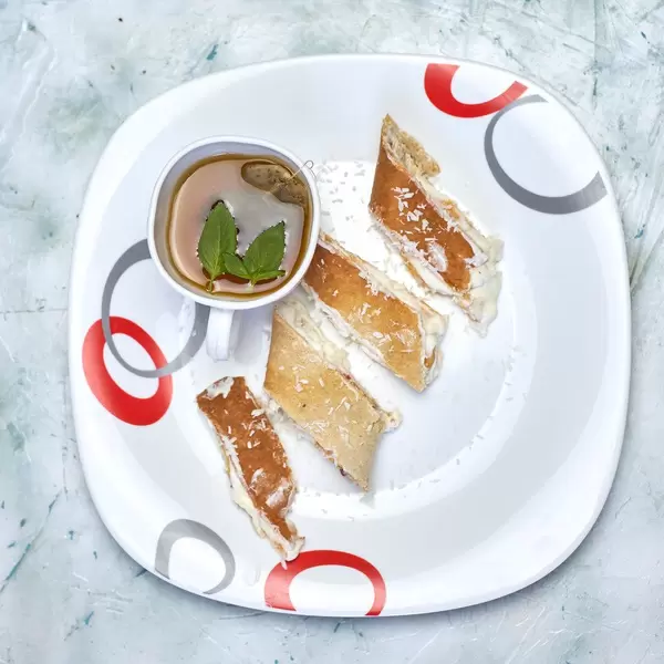 Healthy sweet breakfast. Sliced roulette with soft cottage cheese and a cup of green tea