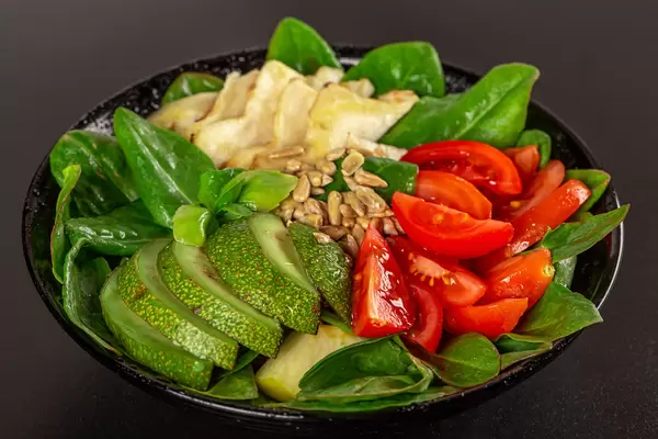 Healthy vegetable salad with sunflower seeds on dark background