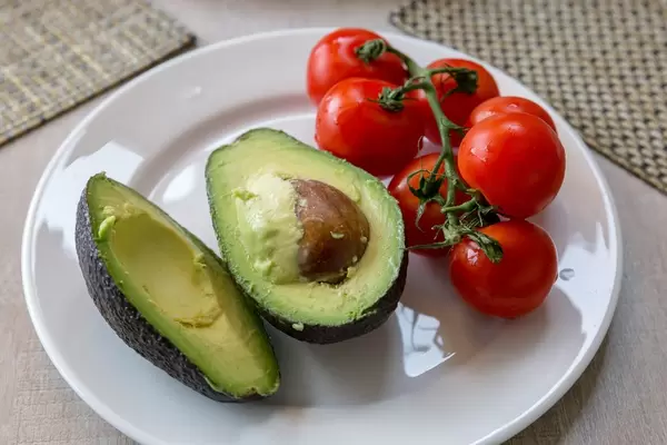 Healthy vegetable snack made of halved avocado and small tomatoes
