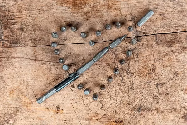 Heart made of screwdriver bits on old wooden background, top view
