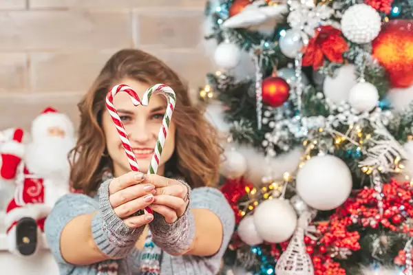Heart made of sweets in the hands of a girl on the background of a christmas tree