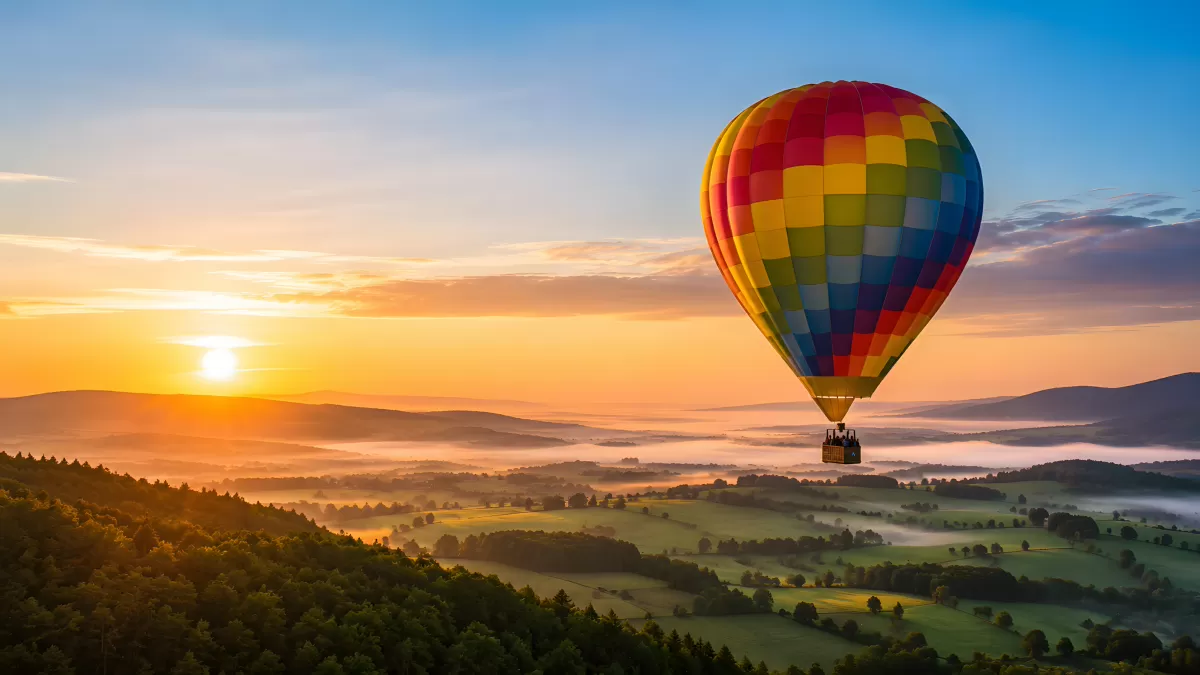 Heißluftballon schwebt über neblige Landschaft im Morgenrot