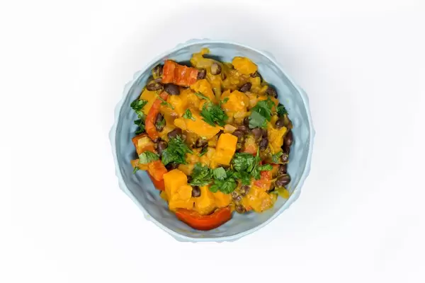 Hello Fresh - Caribbean stew made from sweet potatoes with black beans and coconut milk in a blue bowl on white background