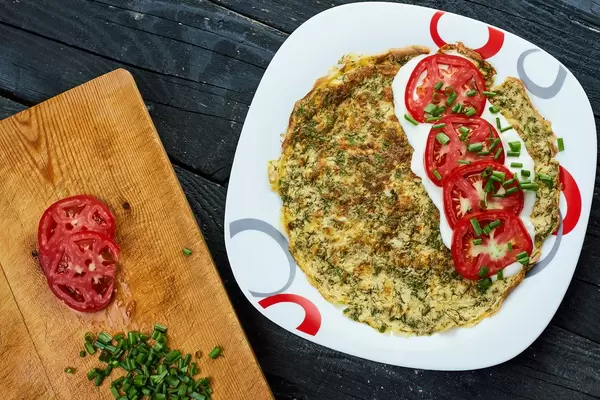 Herbs based omelet and and tomato slices with sour cream