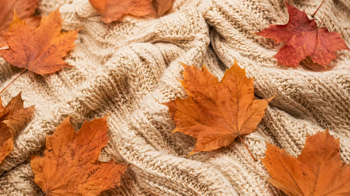 Herbstblätter auf cremefarbenem Strickpullover