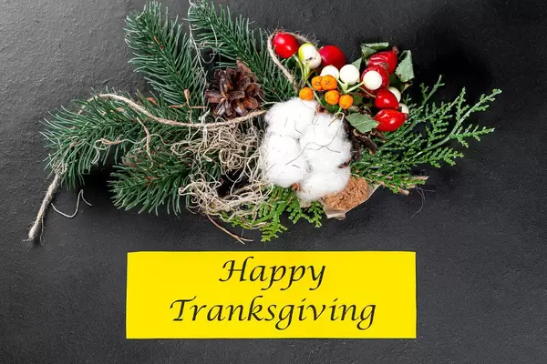 Herbstlicher Tannenzweig mit bunten Früchten und Happy Thanksgiving Schriftzug