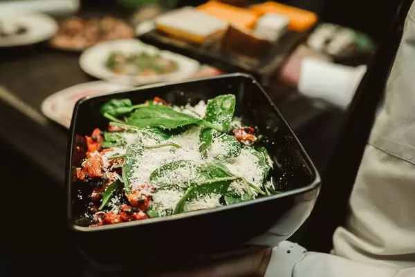 Herbstsalat mit Käse, Äpfel und Moosbeeren in einer schwarzen Schale in einem Restaurant