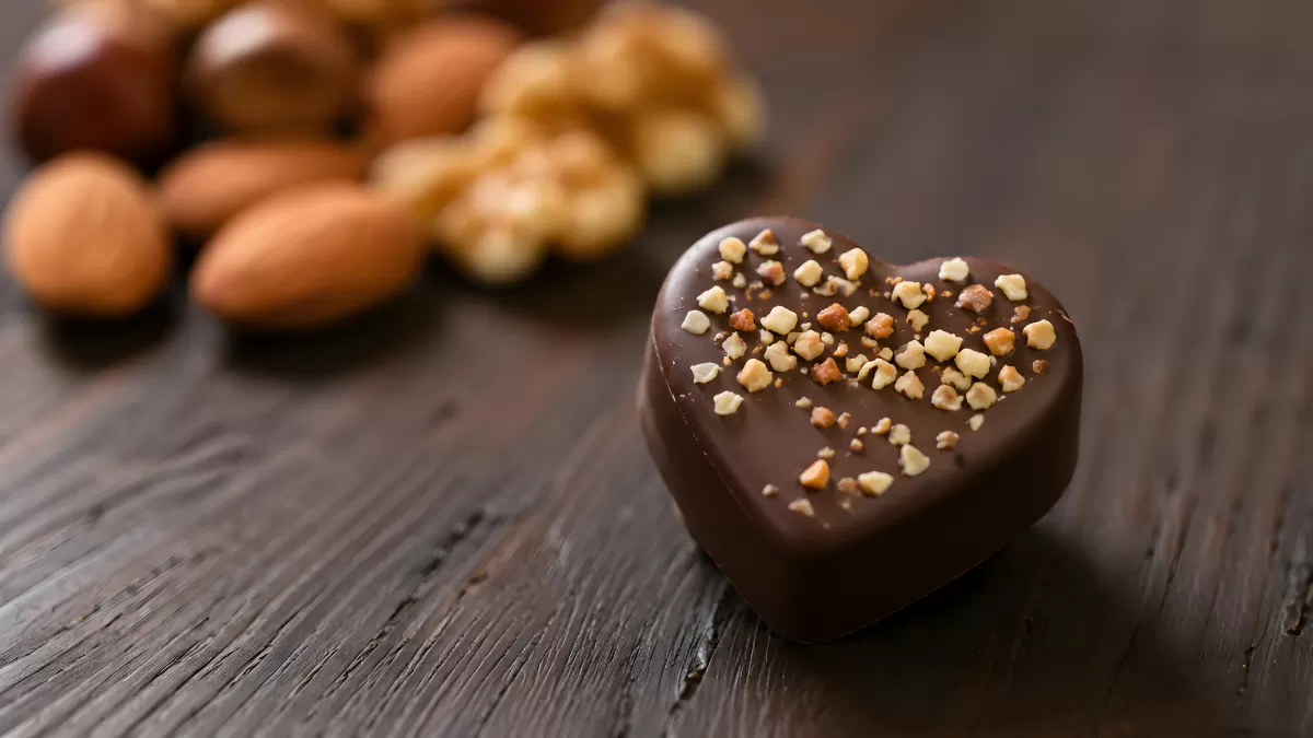 Herzförmige Schokoladenpraline mit gehackten Nüssen