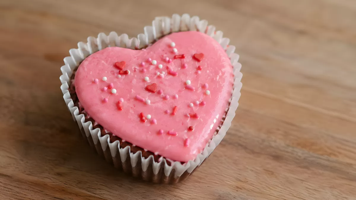 Herzförmiger Cupcake mit rosa Glasur und Streuseln