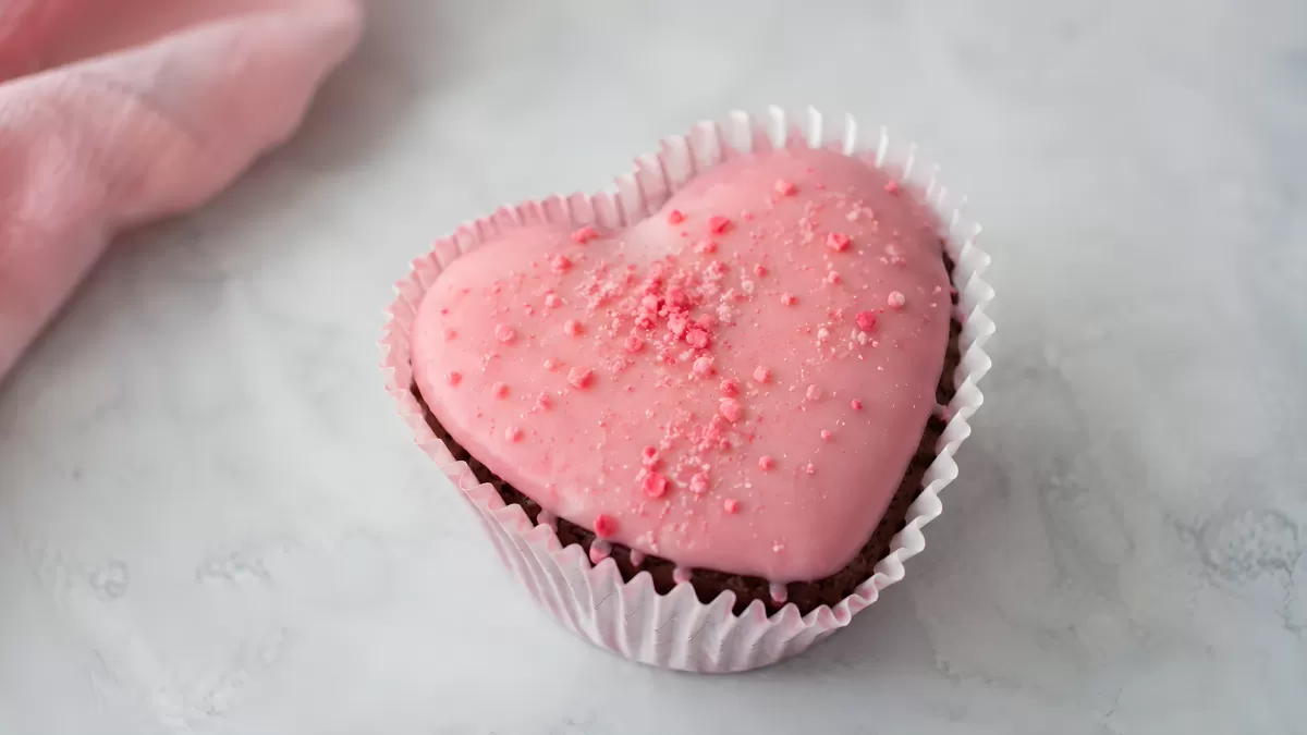 Herzförmiger Cupcake mit rosa Zuckerguss und Streuseln