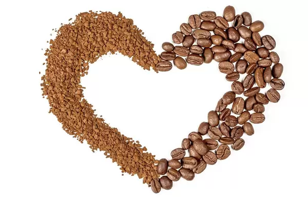 Herzförmiger Kaffee-Rahmen vor weißem Hintergrund. Aufnahme von oben