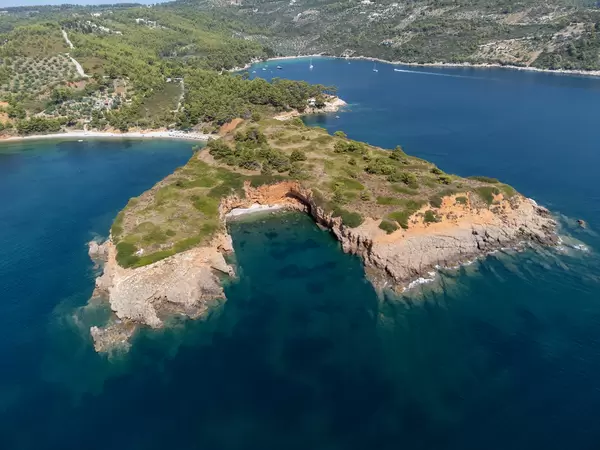 Hidden beach with red cliffs formed by the headland of Kokkinokastro seen from the sea with a drone