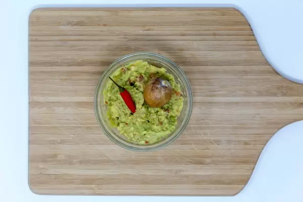 High angle shot - Guacamole Avocado Dip - with red chili pepper and avocado kernel in glas bowl