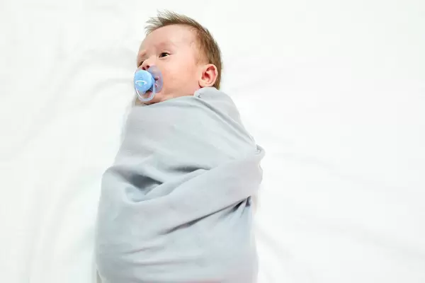 High angle view of cute baby boy wrapped in towel lying on bed at home