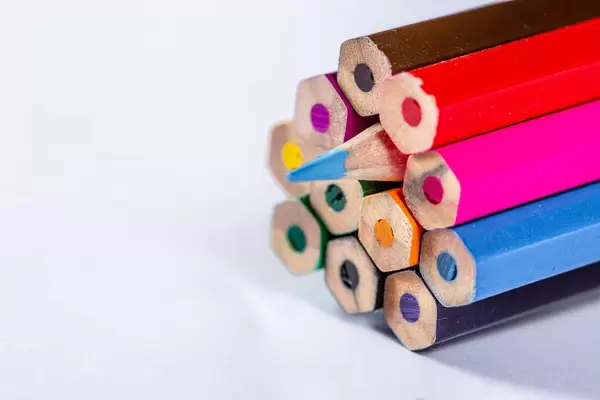 Hinteres Ende von Buntstiften in verschiedenen Farben mit einem umgedrehten Farbstift auf weißem Untergrund