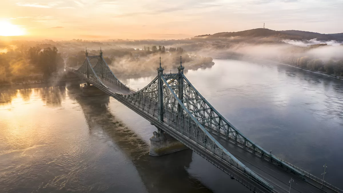 Historische Stahlbrücke im Morgennebel über breitem Fluss