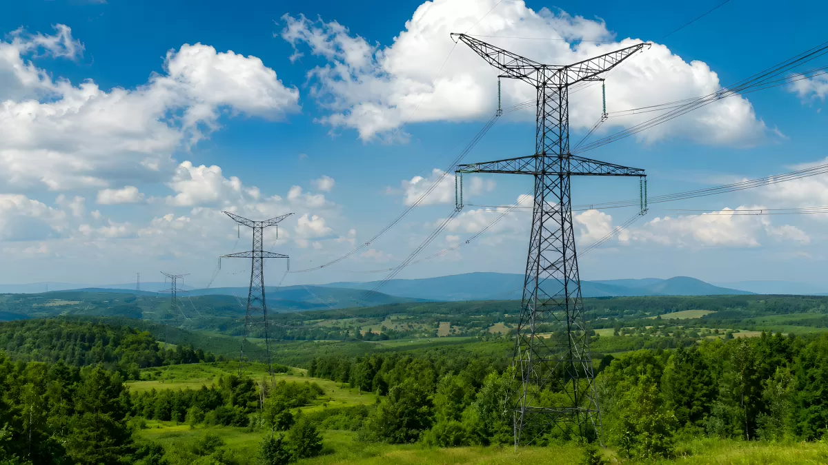 Hochspannungsmasten in grüner Hügellandschaft