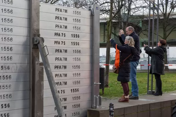 Hochwasserbarrieren und Spaziergänger die den Rhein fotografieren