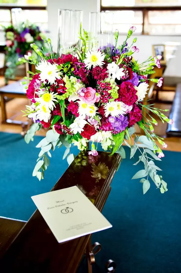 Hochzeits-Blumenstrauß mit dem Hochzeitsprogramm auf einer Bank in der Kirche