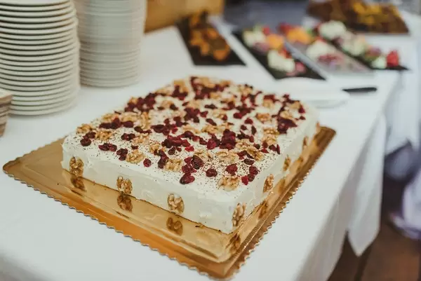 Hochzeitstorte aus Walnuss, Kranichbeeren und Mascarpone auf einem Tisch mit Snacks im Hintergrund