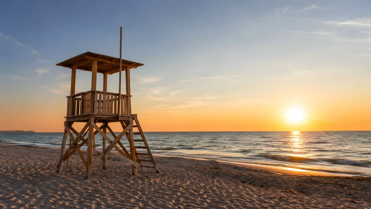 Hölzerner Rettungsturm am Strand bei Sonnenuntergang