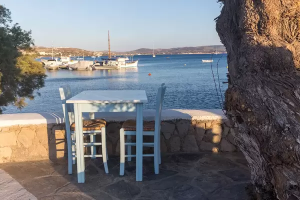 Holiday in Greece, blue table with two chairs and view of the port at a restaurant in Adamantas, Milos