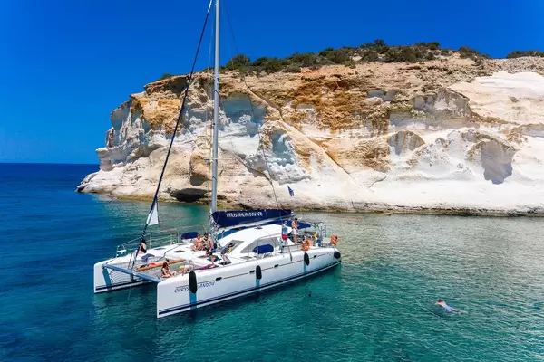 Holiday in Greece: tourists enjoying the sun and the turquoise waters of Milos from a sailing catamaran