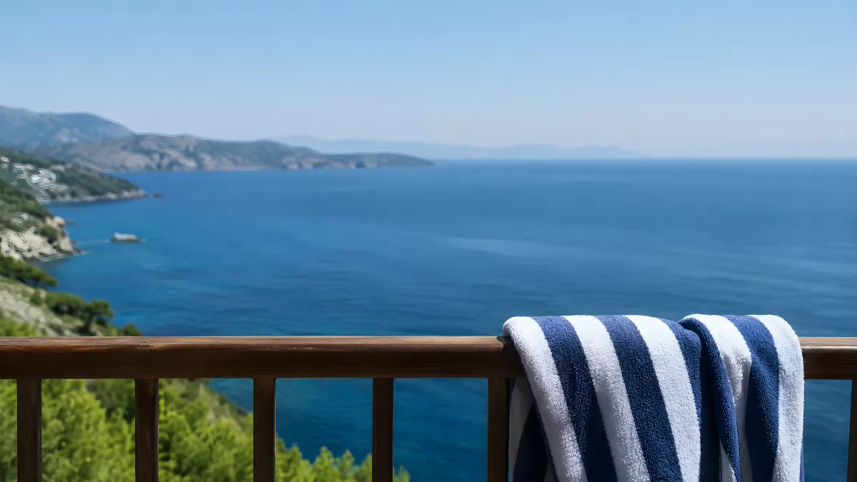 Holzbalkon mit Strandtuch und Meerblick im Sommer