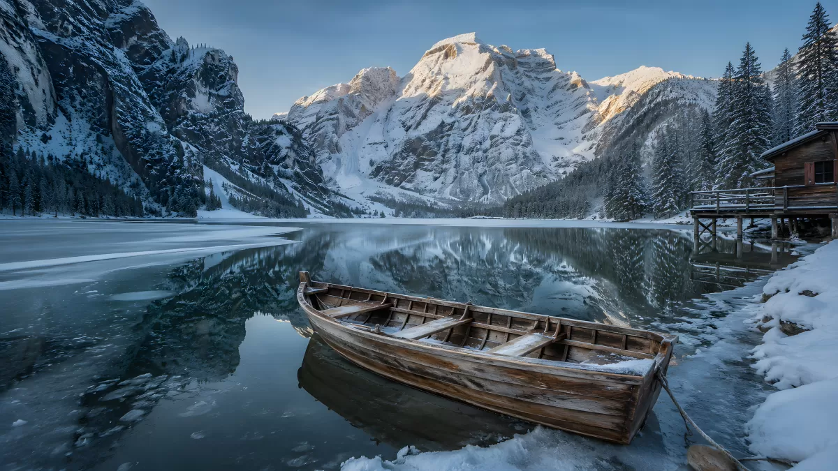 Holzboot am zugefrorenen Bergsee im Winter