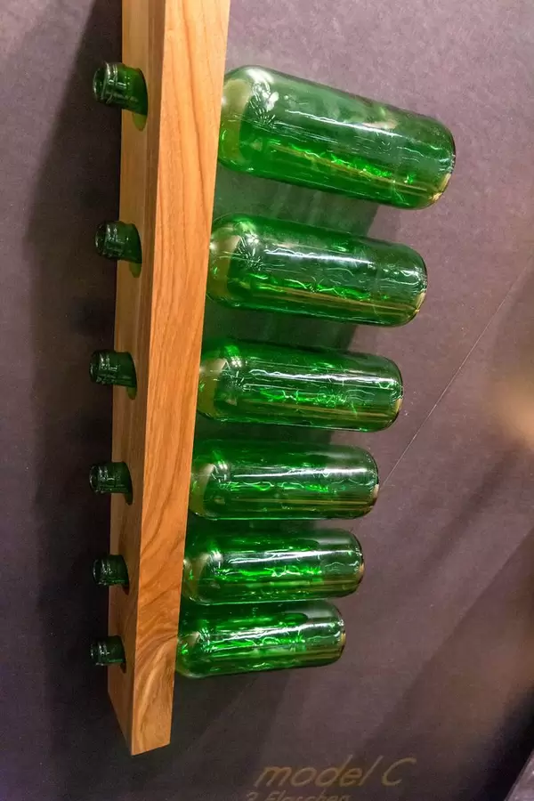 Holzbrett mit Löchern senkrecht an Wand als spezieller Flaschenhalter