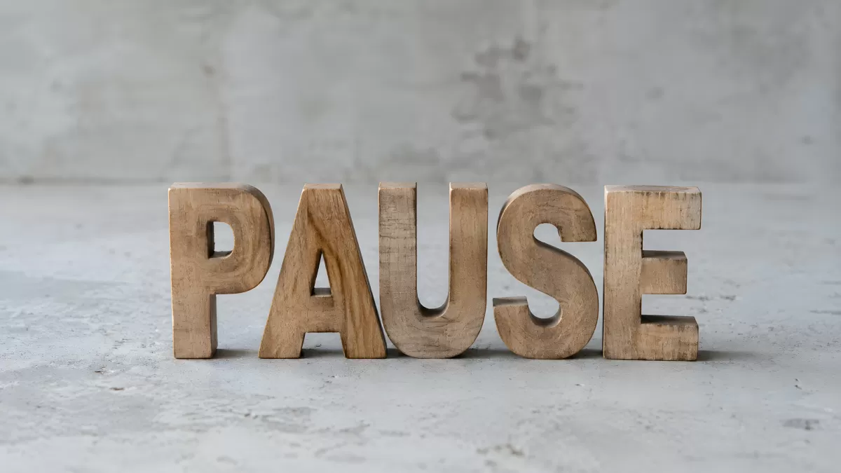 Holzbuchstaben formen das Wort Pause auf Betonuntergrund