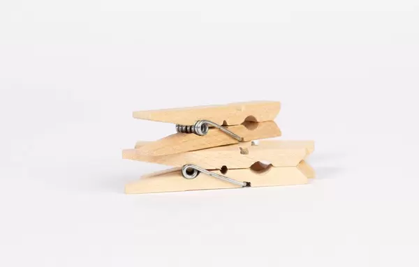 Hölzerne, aufeinander gestapelte Wäscheklammern vor weißem Hintergrund