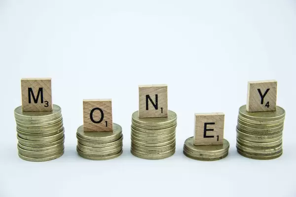 Hölzerne Buchstaben bilden das Wort MONEY auf Türmen aus Münzen