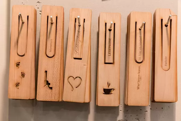 Hölzerne Lesezeichen mit verschiedenen Motiven und Sprüchen auf Nägeln aufgereiht