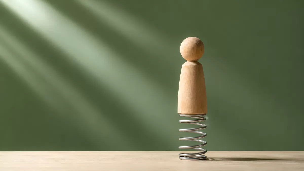 Holzfigur auf Metallspirale als Resilienz-Symbol