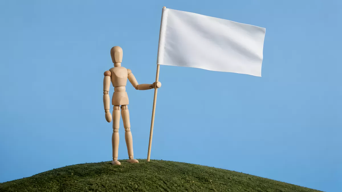 Holzfigur pflanzt weiße Flagge auf grünem Hügel
