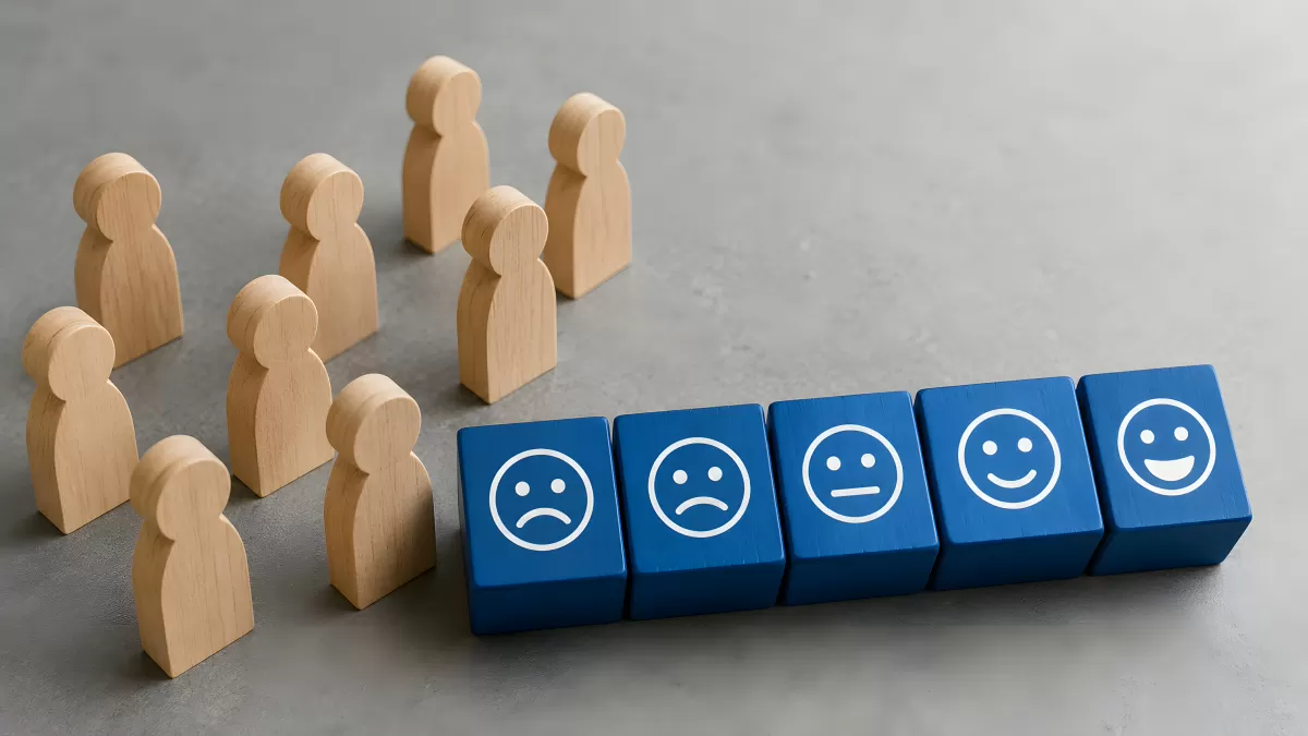 Holzfiguren vor Bewertungsskala mit Smileys auf Blöcken