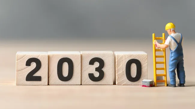 Holzwürfel mit Jahreszahl 2030 und Arbeiter auf Leiter