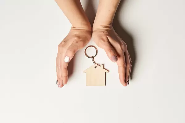 Home insurance concept - hand covering miniature house