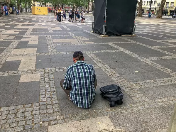 Homeless man and drug addict at Neumarkt in front of visitors of the Cologne art festival "Impulse Theater" in Germany